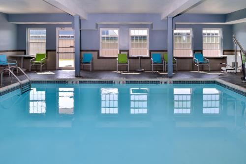 a swimming pool with chairs and tables in a building at Holiday Inn Express Hotel & Suites North Kansas City by IHG in Kansas City