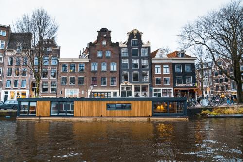 2 Houseboat Suites Amsterdam Prinsengracht في أمستردام: منزل عائم على نهر في مدينة