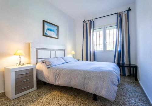 um quarto com uma cama e uma janela com cortinas azuis em El Hidalgo Costa del Sol em Torre de Benagalbón