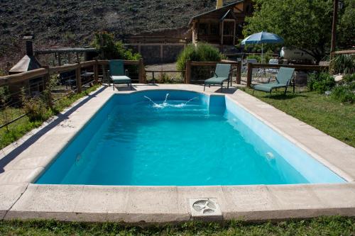 a swimming pool in a yard with two chairs in it at Cabañas del Mesón in Potrerillos
