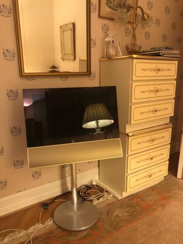 a desk with a lamp and a dresser with a mirror at Villa Elena in Malmö
