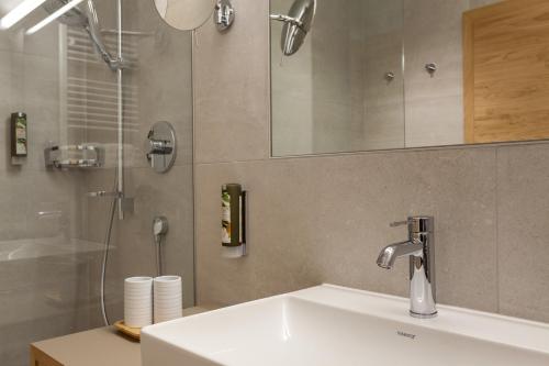a bathroom with a sink with a shower and a mirror at Apart-Hotel Dreisonnenhof in Fiss
