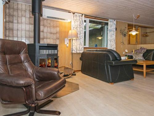 a living room with a leather chair and a fireplace at 6 person holiday home in R m in Bolilmark