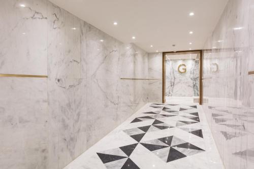 baño con pared de mármol blanco y puerta de entrada en Hotel Excelsior Karachi, en Karachi