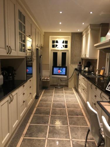 a kitchen with white cabinets and a tv in it at Villa Elena in Malmö