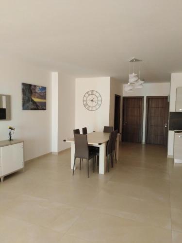 a dining room with a table and chairs and a clock at Paradise in Għajnsielem