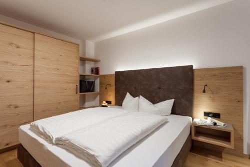 a bedroom with a large white bed and wooden walls at Apart-Hotel Dreisonnenhof in Fiss