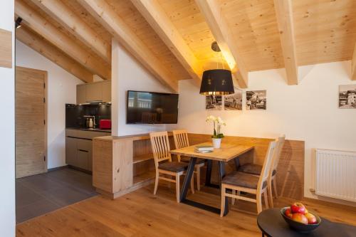 a kitchen and dining room with a wooden table and chairs at Apart-Hotel Dreisonnenhof in Fiss