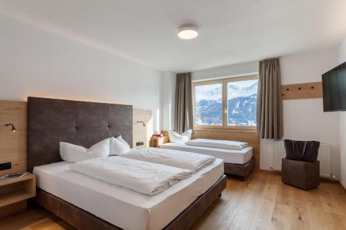 a bedroom with two beds and a large window at Apart-Hotel Dreisonnenhof in Fiss