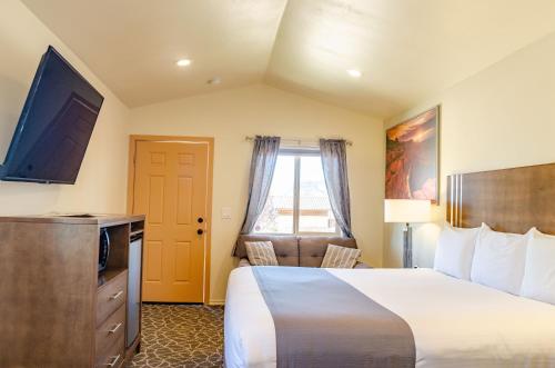 a hotel room with a bed and a flat screen tv at Mountain Ridge Cabins & Lodging Between Bryce and Zion National Park in Hatch