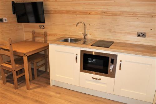 a kitchen with a sink and a table with a microwave at Travellers Rest in Newquay