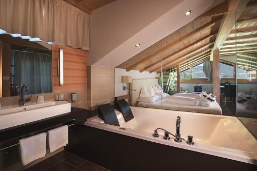 a bathroom with a large tub and a bed at Gartenhotel Völser Hof - Adults Only in Fiè