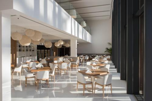 a restaurant with wooden tables and white chairs at Aroeira Lisbon Hotel - Sea & Golf in Aroeira