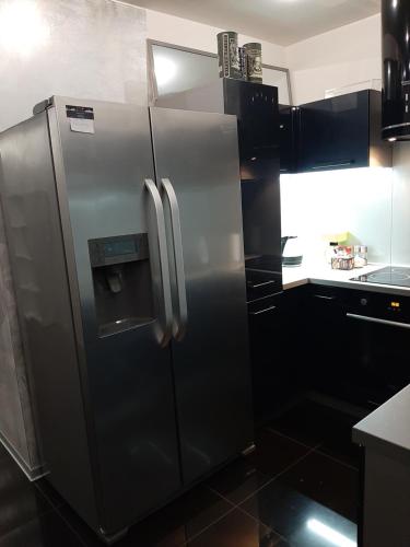 a stainless steel refrigerator in a kitchen with black cabinets at Villa Košice 2 in Košice