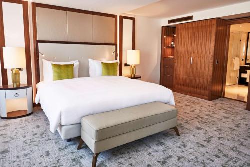 a large bedroom with a large white bed and a stool at Kempinski Hotel Corvinus Budapest in Budapest