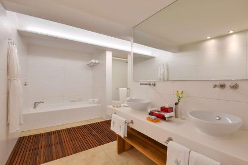 a white bathroom with two sinks and a tub at Kempinski Hotel Aqaba in Aqaba