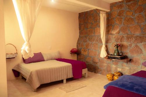 Hotel Juliantla في Juliantla: غرفة نوم بسريرين وجدار حجري