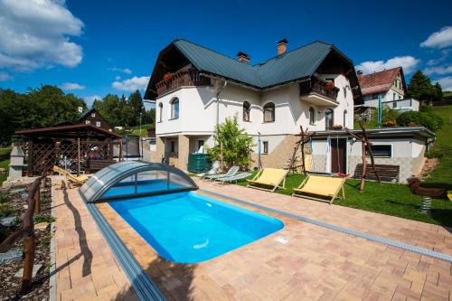 ein Haus mit einem Pool vor einem Haus in der Unterkunft PRIVAT Pacholik in Rokytnice nad Jizerou