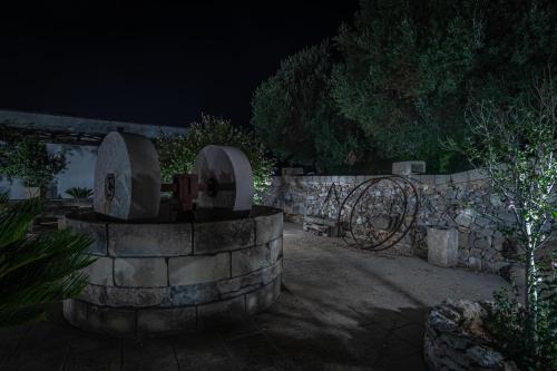 a stone wall with a fountain in a yard at night at Masseria Cinti in Bagnolo del Salento
