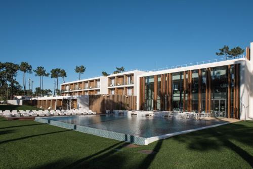 a building with a pool and chairs in front of it at Aroeira Lisbon Hotel - Sea & Golf in Aroeira