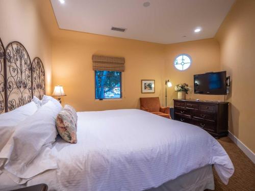 a bedroom with a large white bed and a flat screen tv at Su Nido Inn in Ojai