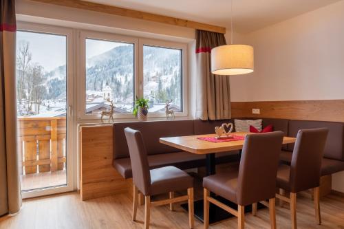 a dining room with a table and chairs and a large window at Appartement Schattauer in Wagrain