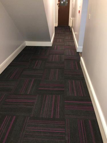 a hallway with a carpeted floor and a stairway at Queens Guesthouse Manchester in Manchester