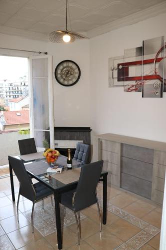 une salle à manger avec une table, des chaises et une horloge murale dans l'établissement Maison Niçoise au calme vue mer, à Nice