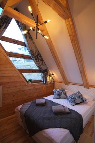 a bedroom with a large bed in a attic at Domek & Apartament Na Ogrodzie in Suche
