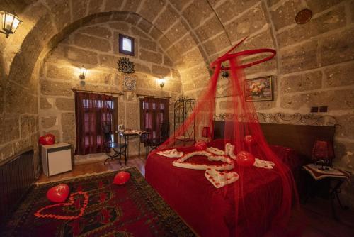 a bedroom with a red bed in a stone room at Kapadokya Ihlara Konaklari & Caves in Guzelyurt