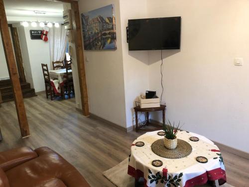 Una sala de estar con una mesa y un televisor en la pared. en Gîte de l'Est 1, en Colmar