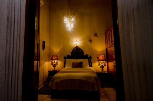 a bedroom with a bed with a chandelier and two lamps at Hotel Posada San Miguel in Jerez de García Salinas