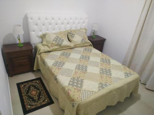 1 dormitorio con 1 cama con edredón y 2 mesitas de noche en Alojamiento Vio Plaza Villa Elisa en Villa Elisa
