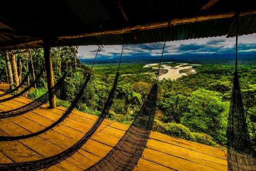 a hammock on a deck with a view of a river at Guest House Great Hostels Amazon in Puyo