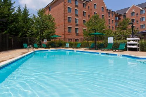 a large swimming pool with chairs and a building at Staybridge Suites Tysons - McLean by IHG in McLean
