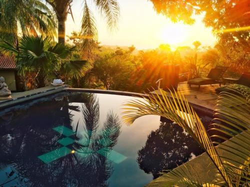 a swimming pool with a sunset in the background at Finca Los Caballos Montezuma in Montezuma