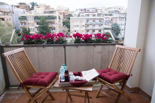 a table and two chairs on a balcony with flowers at JSK Suite in Rome