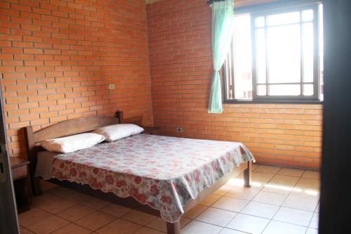 1 dormitorio con 1 cama en una pared de ladrillo en Pousada ACM Tramandaí - RS, en Tramandaí