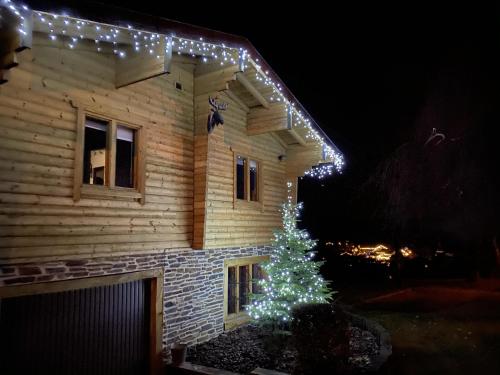 a christmas tree in front of a house with lights at Chalet de Charme in Rochehaut
