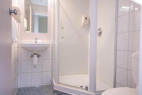 a bathroom with a shower and a sink and a toilet at Hotel Waterloo & Backpackers in Wellington