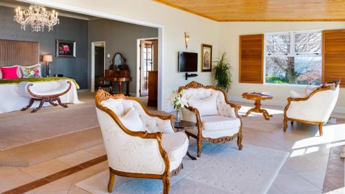 a living room with chairs and a bed at On The Point - Lake Rotorua in Rotorua