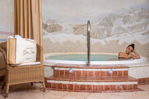 a woman in a jacuzzi tub with a painting at Hotel Gran Fanes in Corvara in Badia