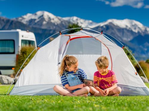 two children sitting in front of a tent at Kaikōura TOP 10 Holiday Park in Kaikoura