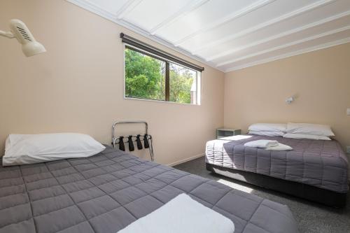 a bedroom with two beds and a window at Blue Lake TOP 10 Holiday Park in Rotorua