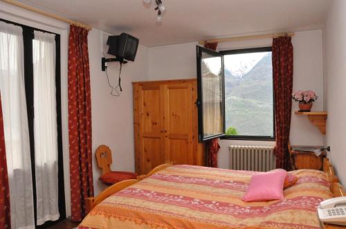 1 dormitorio con 1 cama, TV y ventana en Hotel Bellavista, en Teglio