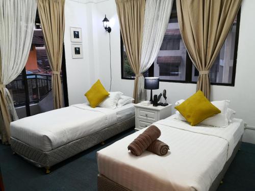 a bedroom with two beds with yellow pillows at Vitatree Cottage in Kuah