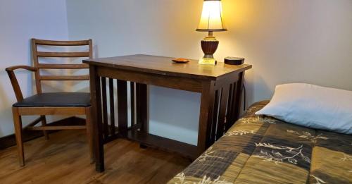 a desk with a lamp and a chair next to a bed at Little River Inn Motel in Leon