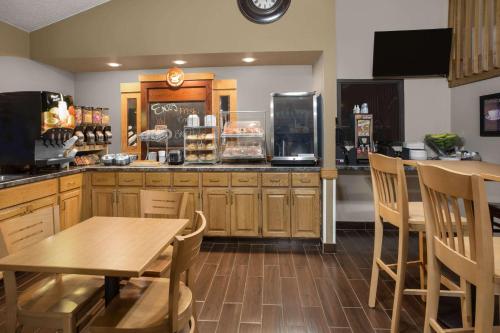 a kitchen with wooden cabinets and a table and chairs at AmericInn by Wyndham Sioux City in Sioux City