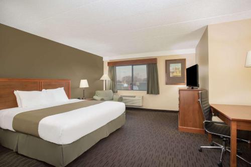 a hotel room with a large bed and a desk at AmericInn by Wyndham Sioux City in Sioux City