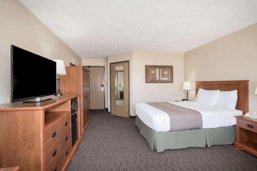 a hotel room with a bed and a flat screen tv at AmericInn by Wyndham Sioux City in Sioux City